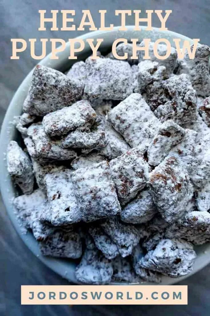 This is a pinterest pin for healthy puppy chow. There is a white bowl filled with chex cereal covered in chocolate and peanut butter coating and white powdered sugar.